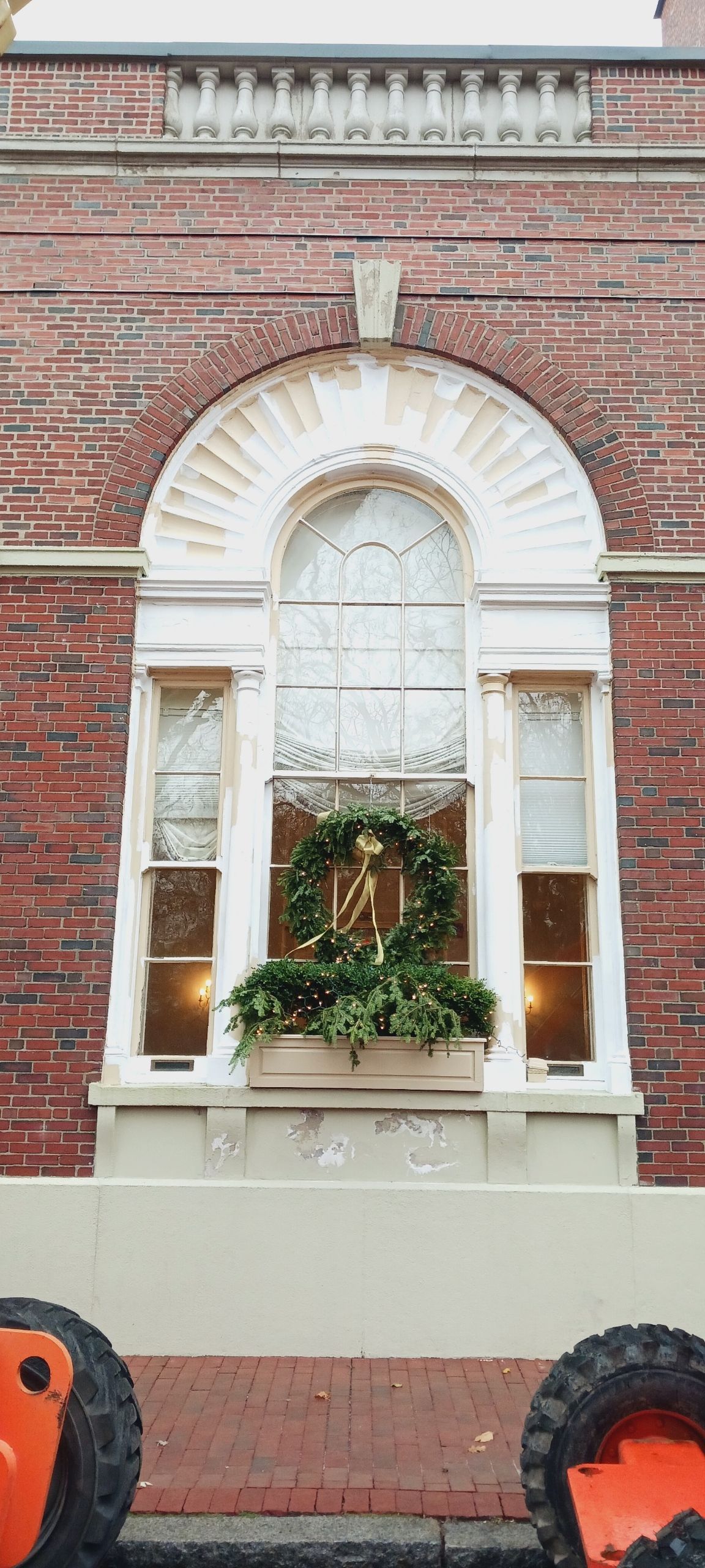 A brick building with a window with a wreath in it.