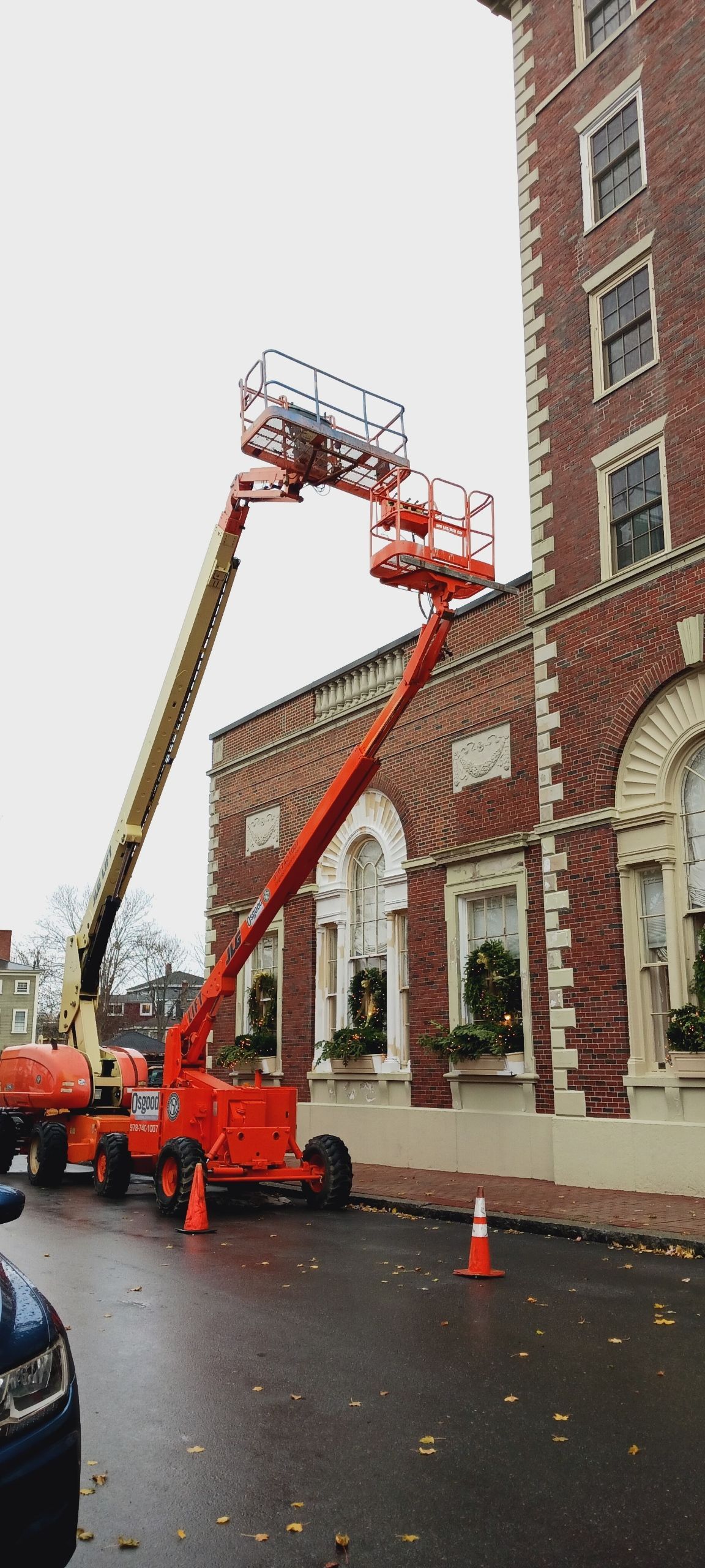 A crane is parked in front of a large brick building.