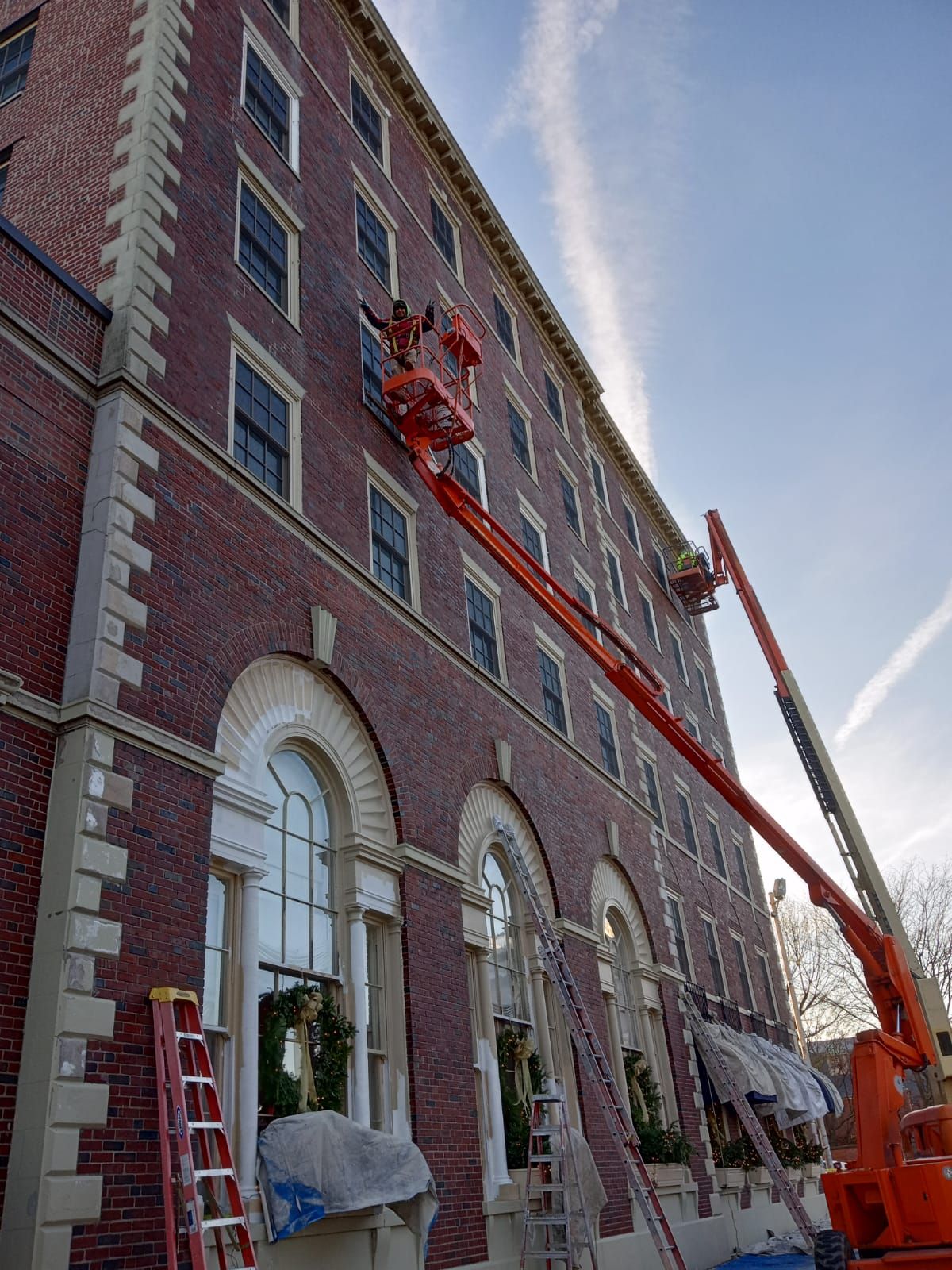A large brick building is being painted with a crane.