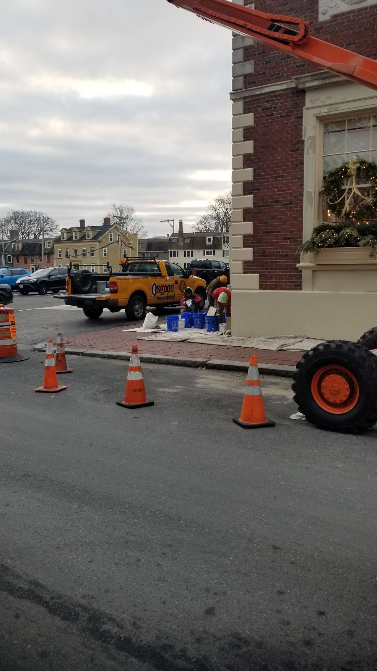 A yellow truck is parked in front of a brick building.