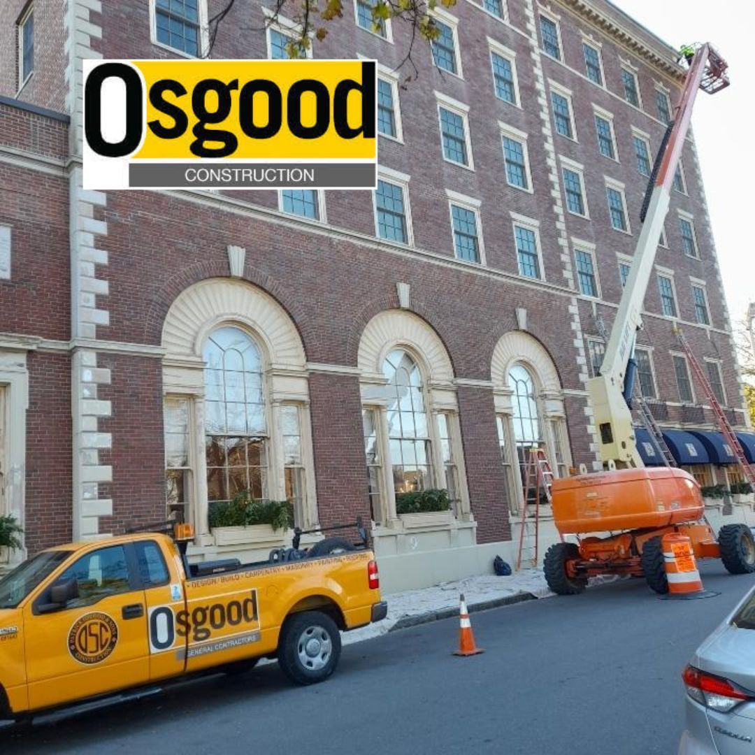 A yellow Osgood truck is parked in front of a large brick building.