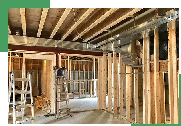 Interior under renovation with exposed wooden framing, beams, ladders, and construction tools