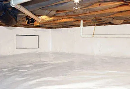 White basement interior with plastic-covered floor, painted walls, exposed ceiling beams, and pipes