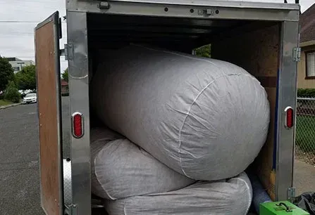 Oversized white bags packed tightly inside an open cargo trailer