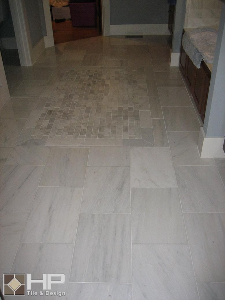Light gray tiled floor in a hallway with damaged tile in the center