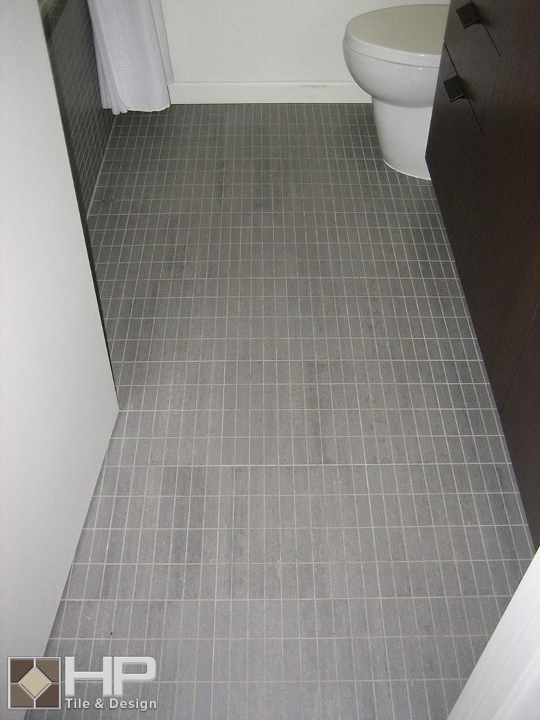 Gray bathroom floor with rectangular tiles, toilet, and white door