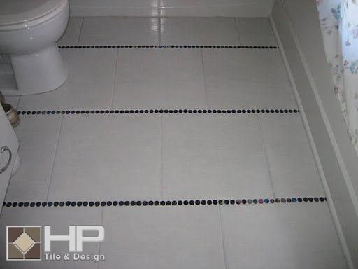 White tiled bathroom floor with blue mosaic accents