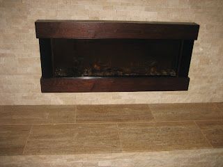 Fireplace with dark wood trim in a tile-walled setting.