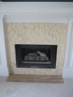 Fireplace with beige mosaic tile surround and black insert; white mantel.