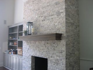 Stone fireplace with wooden mantel and built-in bookshelves on the left.