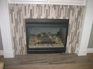 Fireplace with gray, brown, and white tile surround and hearth, set in a white-trimmed mantel.