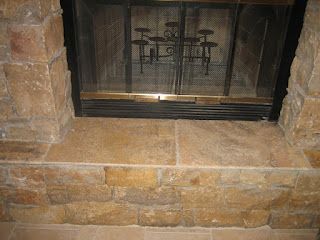 Fireplace with a stone exterior and a black mesh screen.