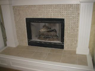 Fireplace with tan tiles and a black firebox, flanked by white columns.