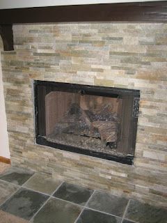 Fireplace with stacked stone surround, dark frame, and tiled hearth.
