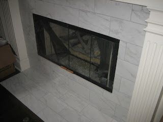 Fireplace with white tile surround and black screen.
