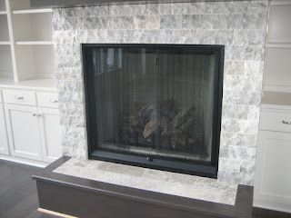 Fireplace with gray tile surround, black frame, and built-in white cabinets on either side.