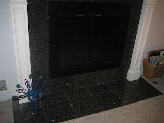 Black tiled fireplace with black doors, white trim, and peacock decor.