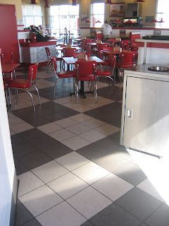 Red and white diner interior with checkered floor, tables, and chairs.