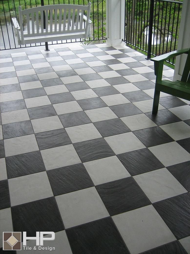 Black and white checkerboard flooring on a porch, with a white swing and green chair visible