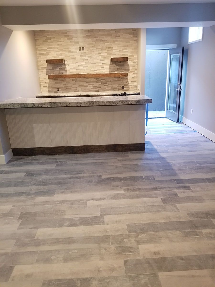 Basement with bar, stone backsplash, shelves, granite countertop, light wood-look floor