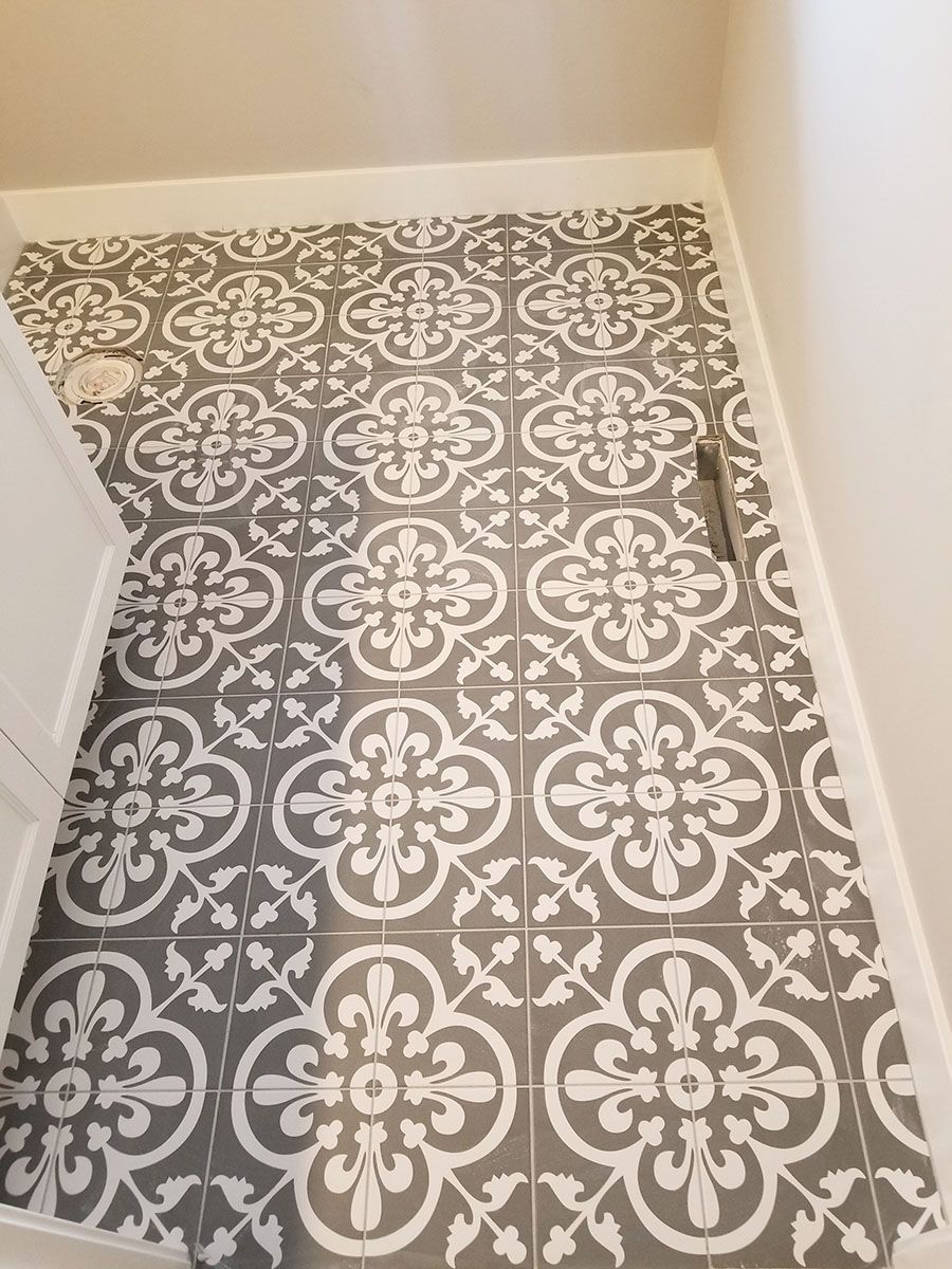 Gray and white patterned tile flooring in a small bathroom with white walls and trim