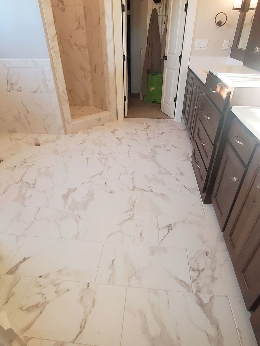 Marble tile bathroom floor, shower stall, dark wood vanity, and doorway to a closet