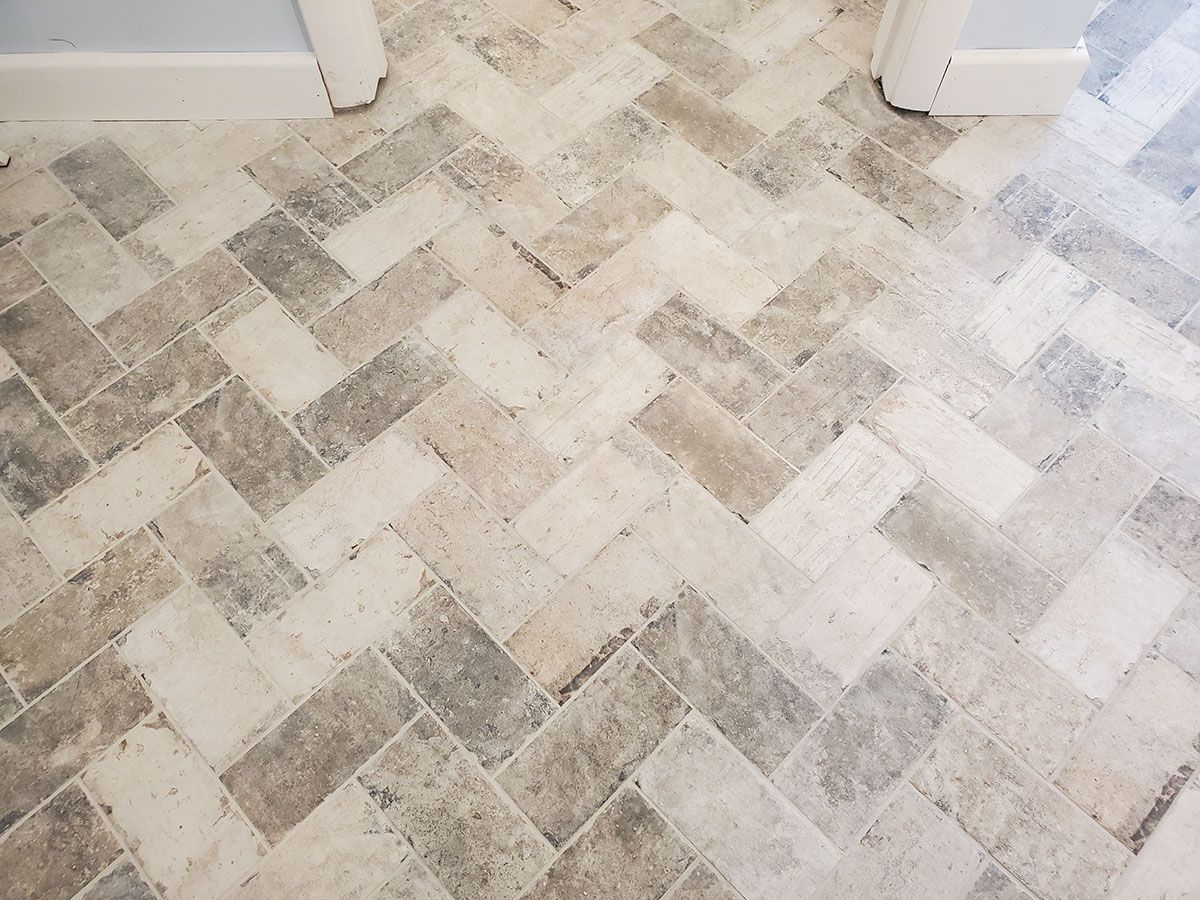 Herringbone pattern floor tiles in varying shades of gray and beige