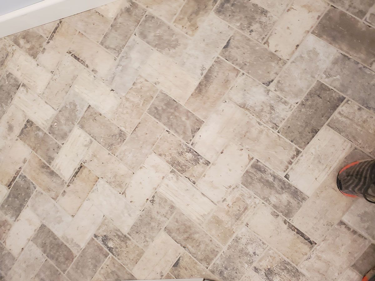 Herringbone patterned floor tiles in shades of beige and gray