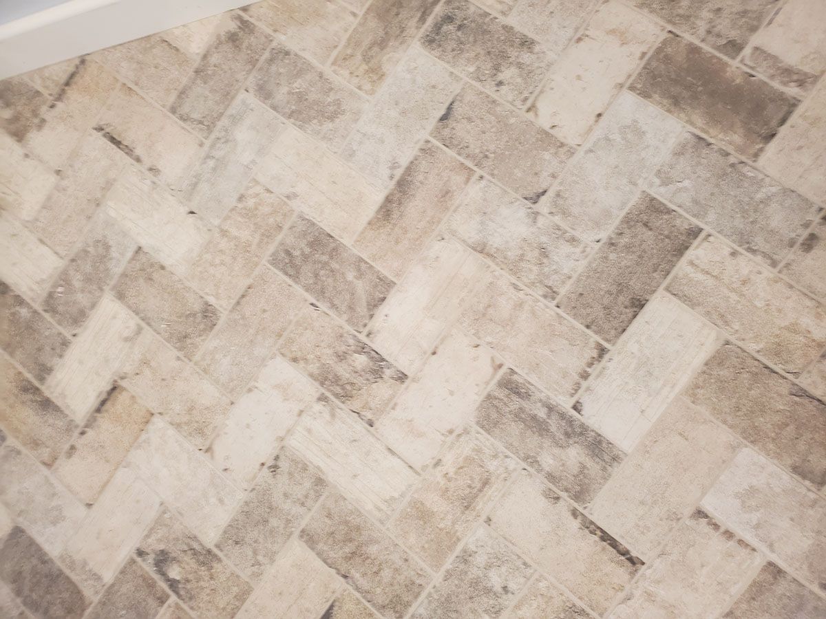 Herringbone tile floor pattern in light beige and gray tones