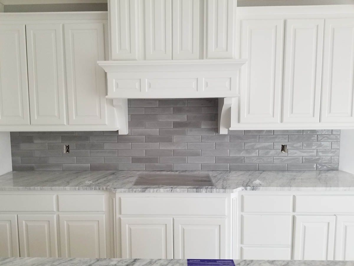 White kitchen with gray backsplash, cabinets, and countertop