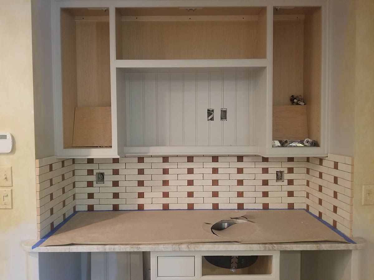 Kitchen backsplash under construction, white and red tile installed