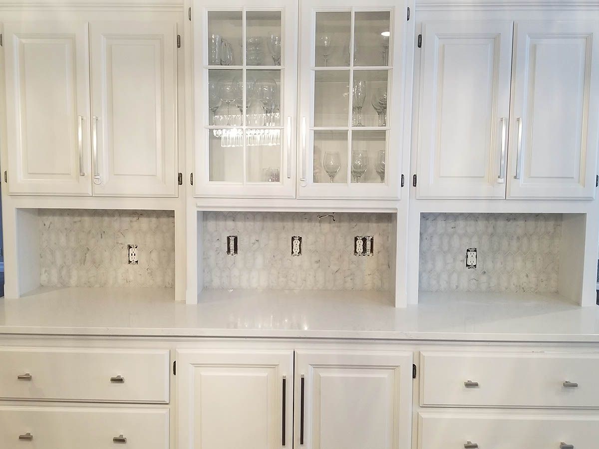 White kitchen cabinets with built-in glass-front display case, and backsplash