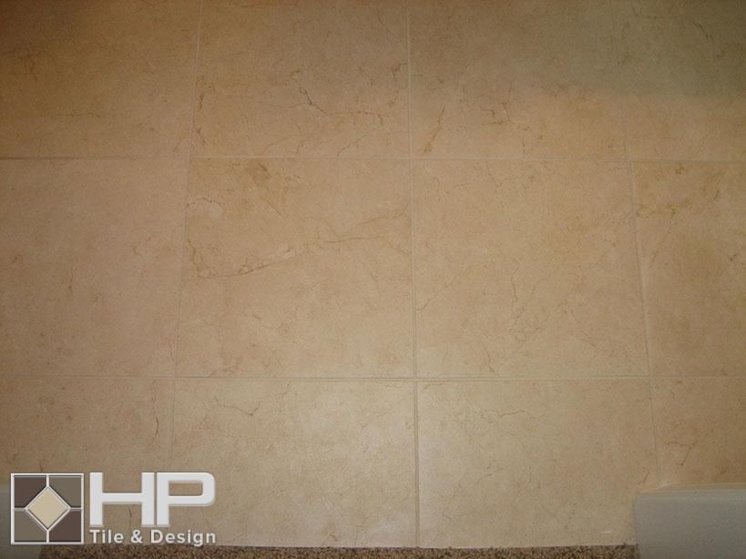 Beige tiled wall with a brown countertop and the HP Tile & Design logo