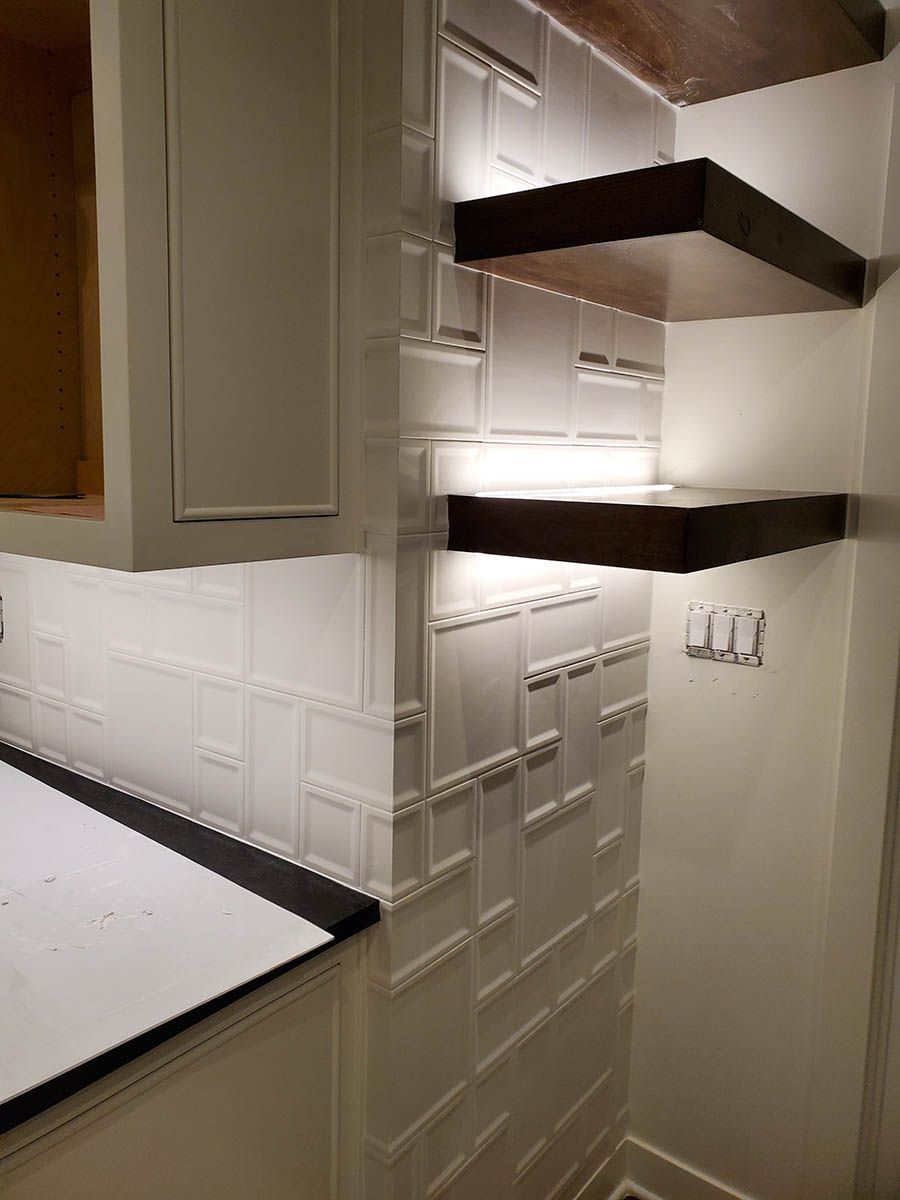 White tiled kitchen backsplash and floating shelves with under-shelf lighting