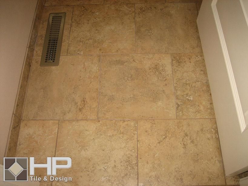 Tan tile floor with a vent and the edge of a white cabinet