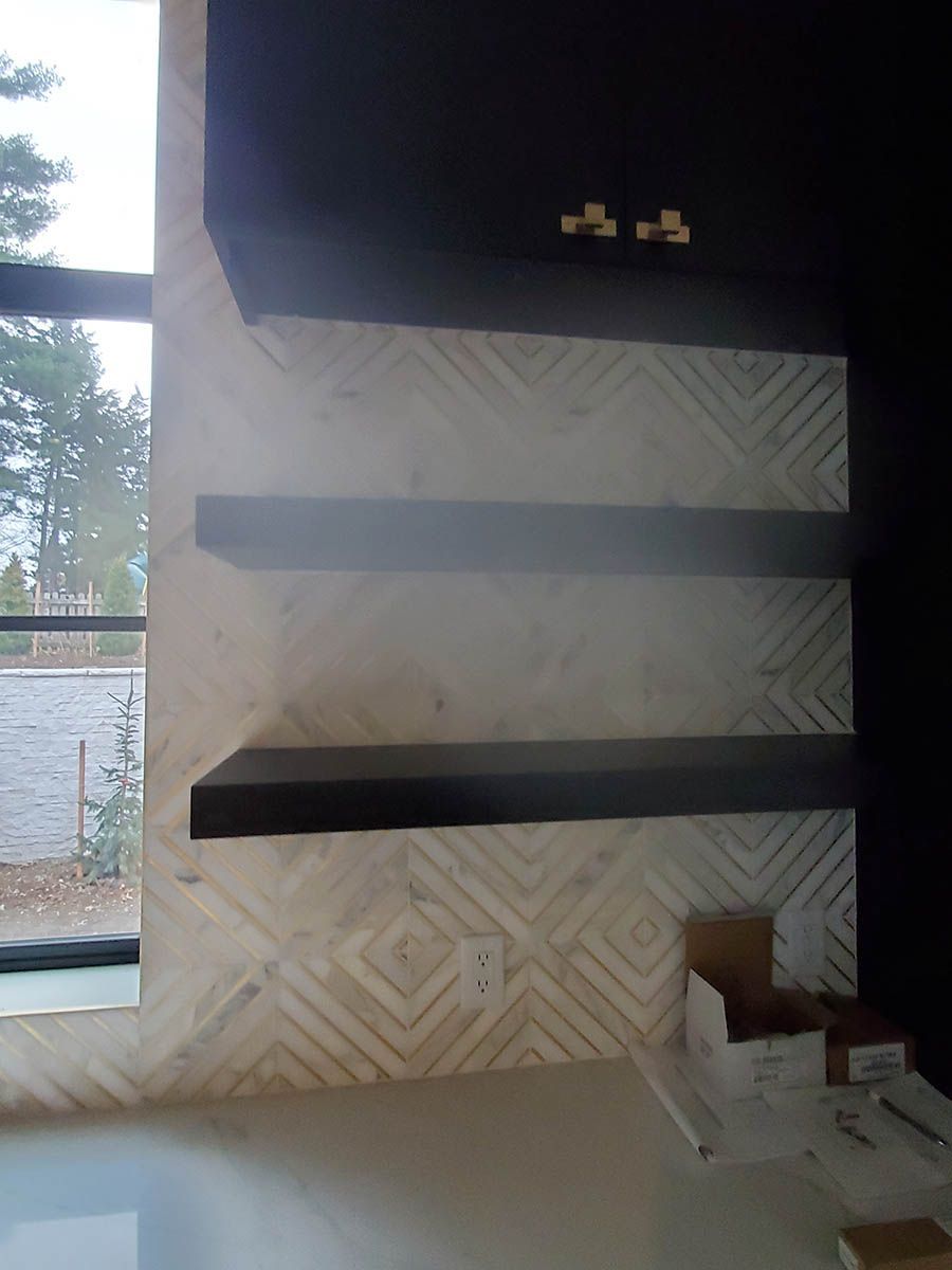 Three black shelves mounted on a wall with geometric patterned, light-colored tile