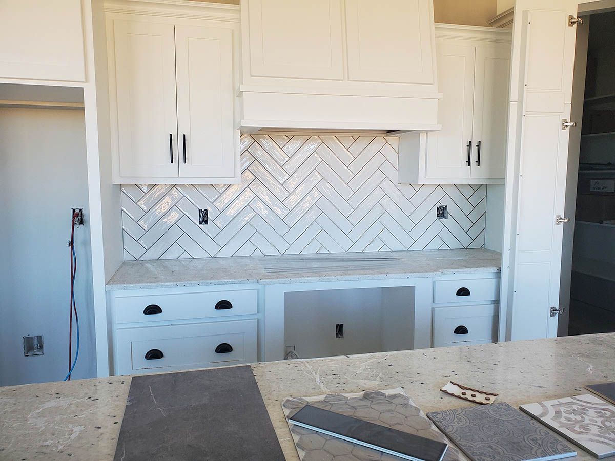 White kitchen cabinetry with a herringbone backsplash