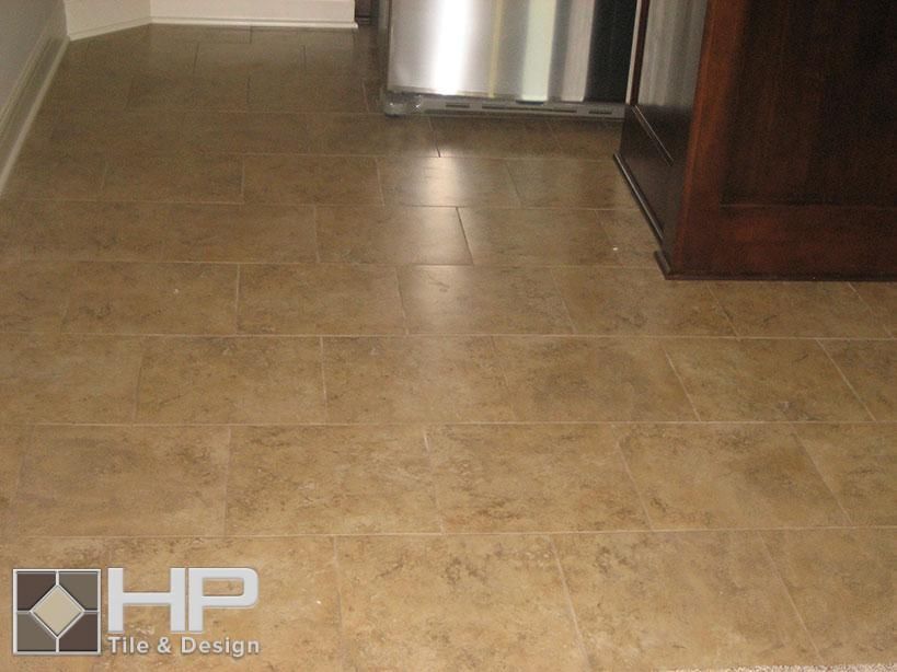 Tan tile floor with a dark wood cabinet on the right and a stainless steel appliance in the back