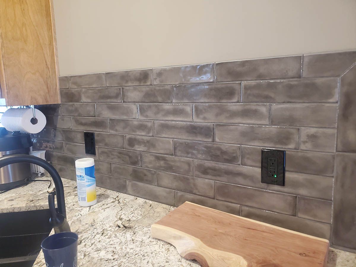 Gray brick-style backsplash with two electrical outlets, installed in a kitchen