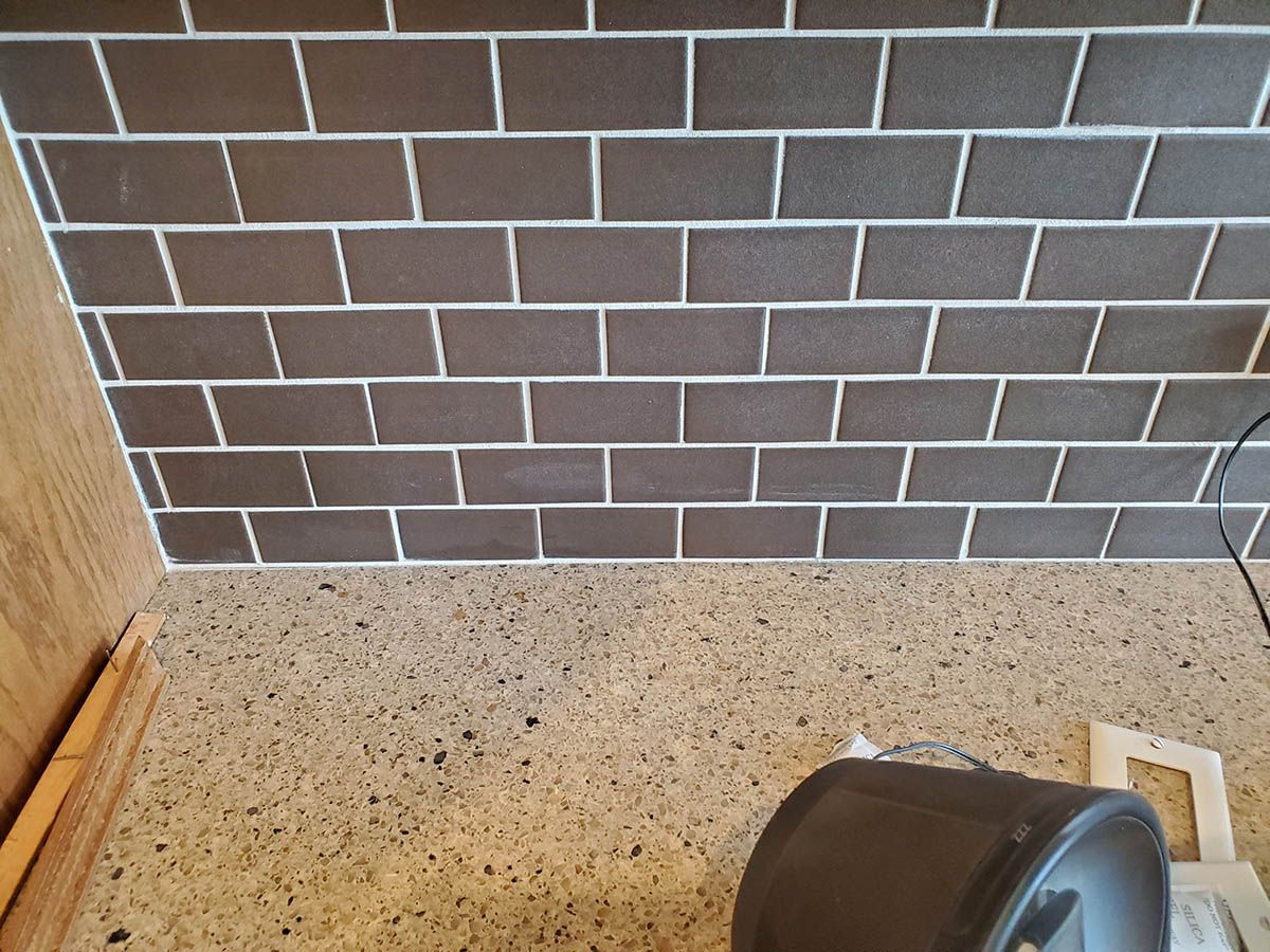 Brown tile backsplash with light grout, above a speckled countertop