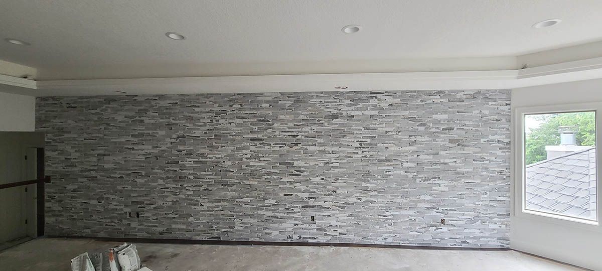 Interior view of a room with a brick accent wall, white ceiling, and a window