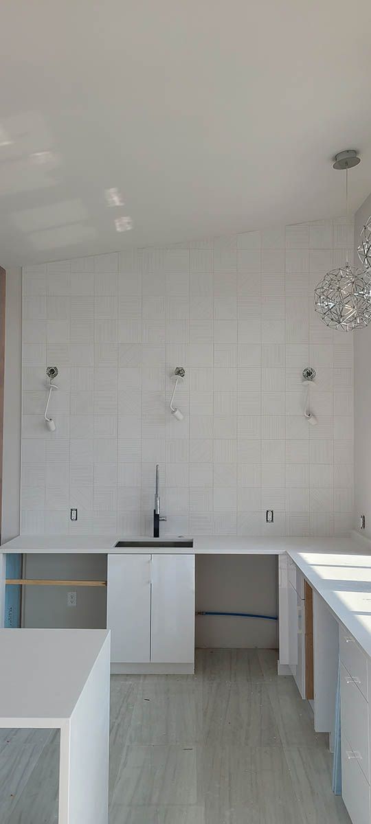 Kitchen with white cabinets, white tile backsplash, and a black faucet