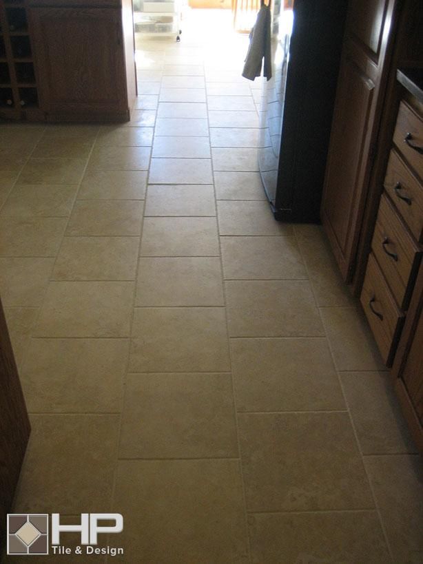 Beige tile floor in kitchen with wooden cabinets and a doorway