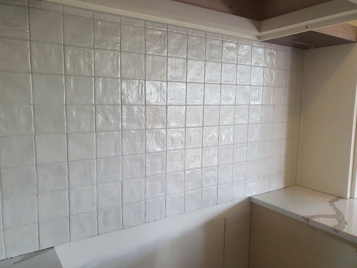White square tiles cover a kitchen backsplash above a countertop