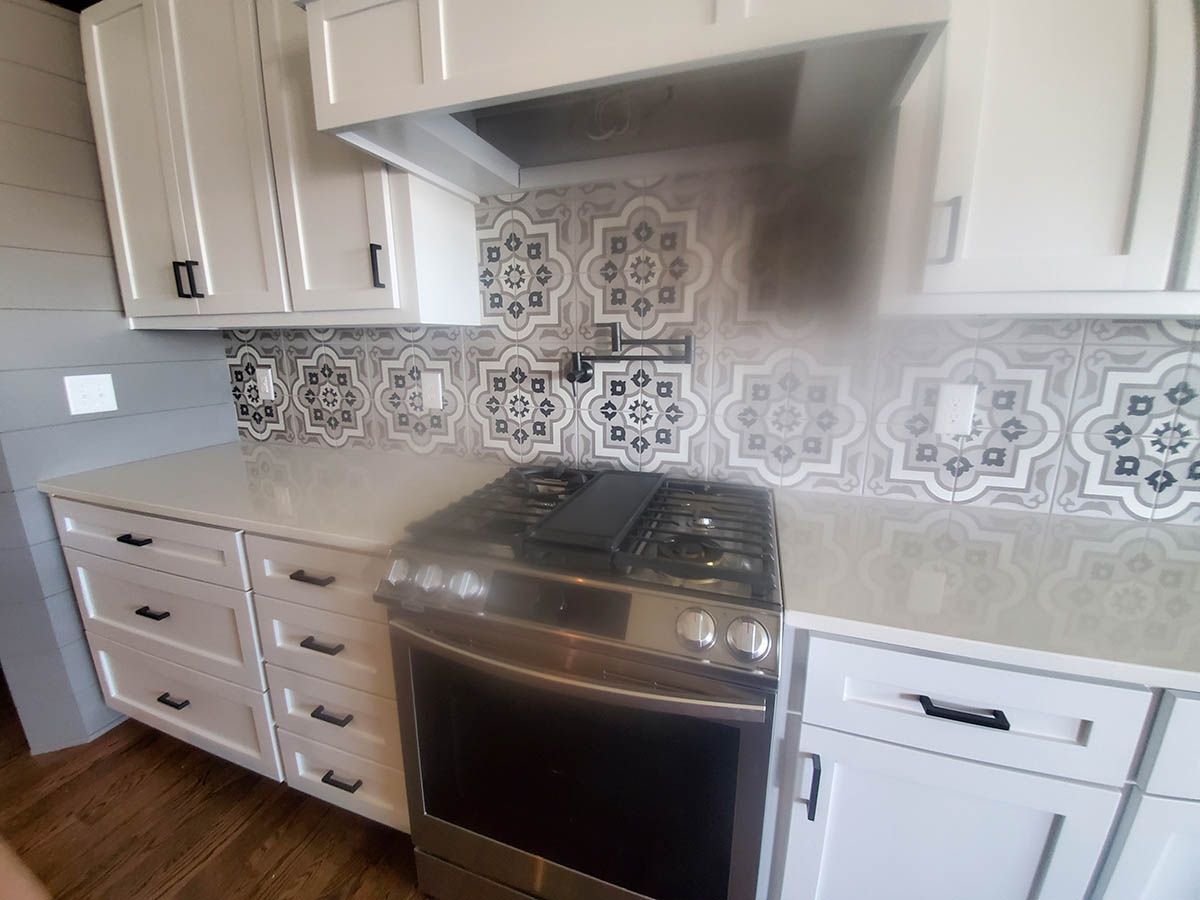 White kitchen with stove, cabinets, and patterned backsplash tile
