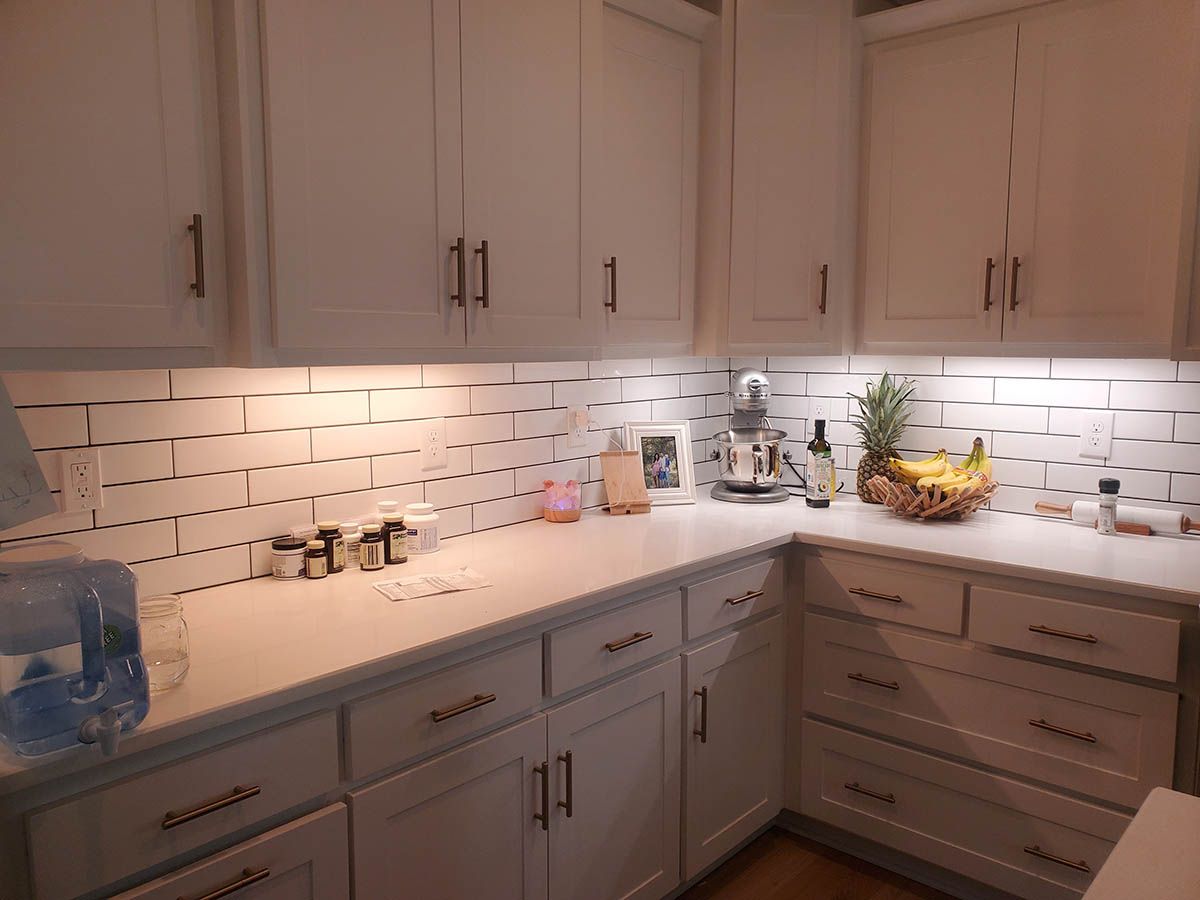 White kitchen cabinets with white countertops and white tiled backsplash