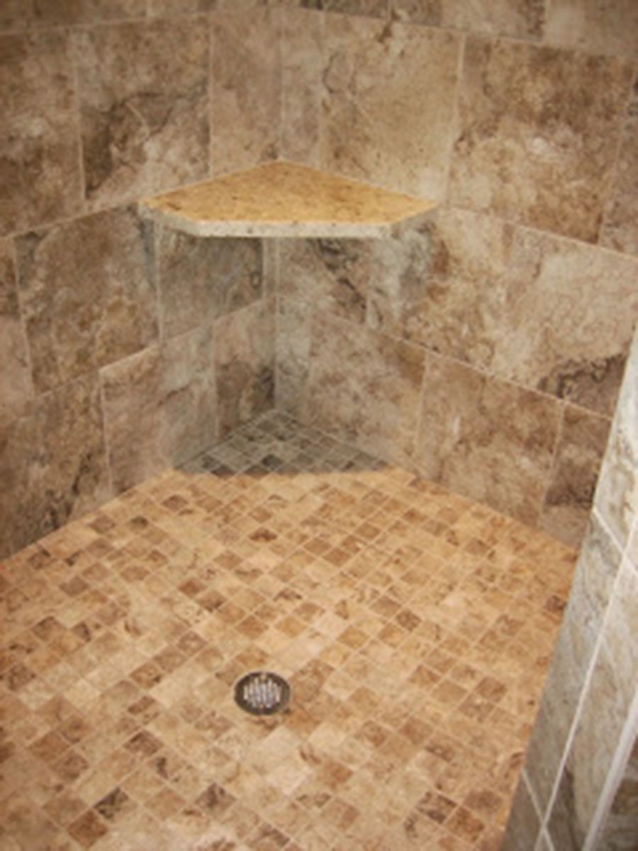 Shower with tan and brown tiles, corner shelf, and small square tile floor