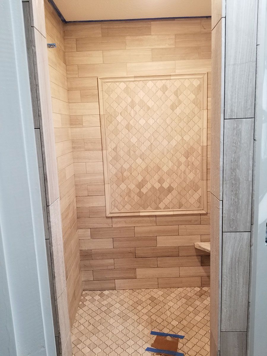 Newly tiled shower with light brown wood-look tiles