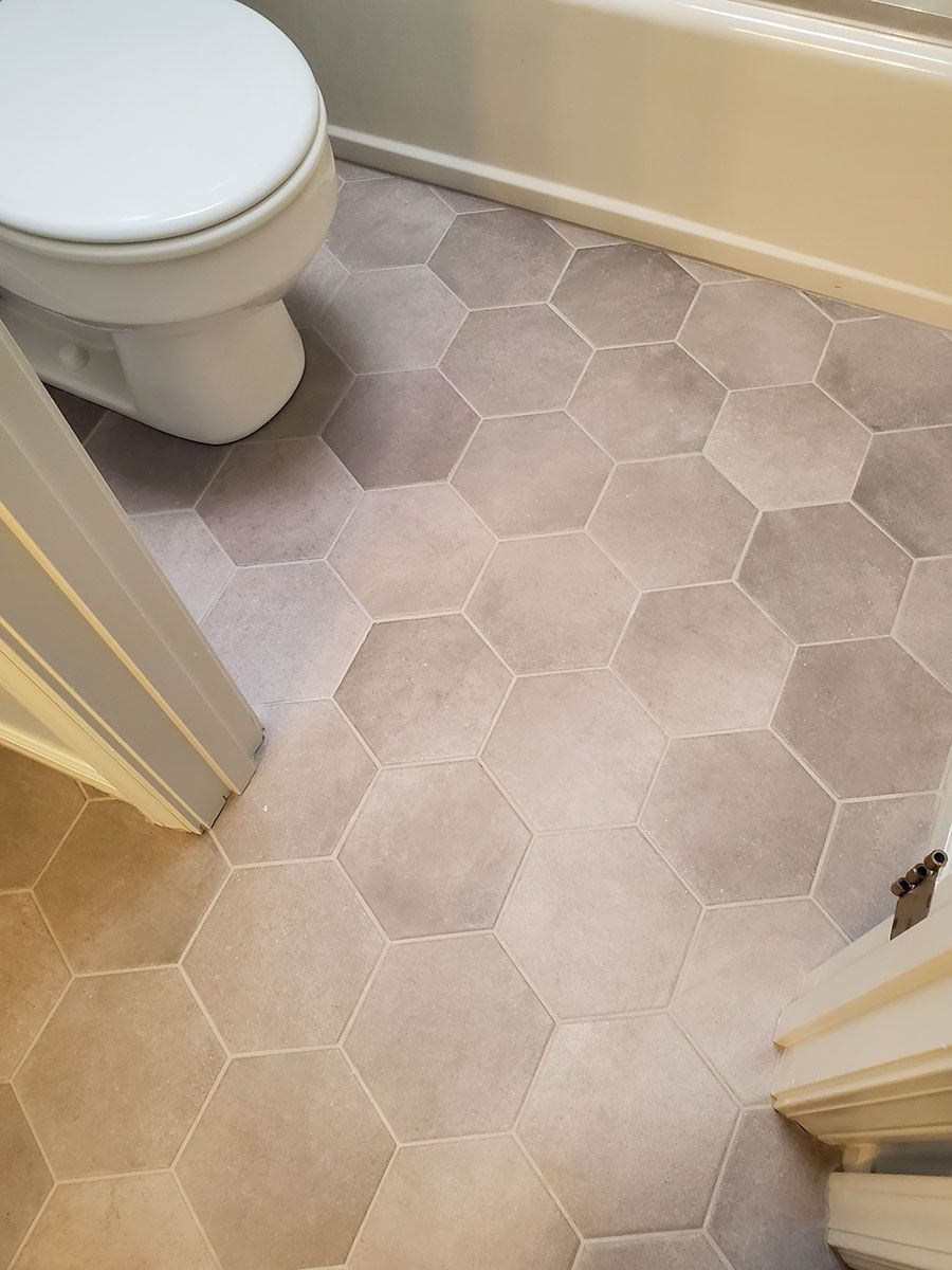 Bathroom floor with gray hexagon tiles, adjacent to a white toilet and tub