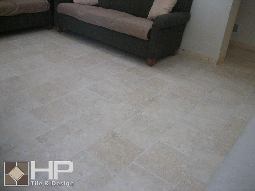 Beige tiled floor with dark green sofa, brown cushions in a living room